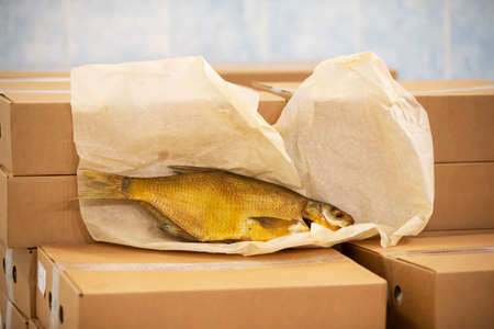 Smoked mackerel lies on cardboard boxes in a warehouse.