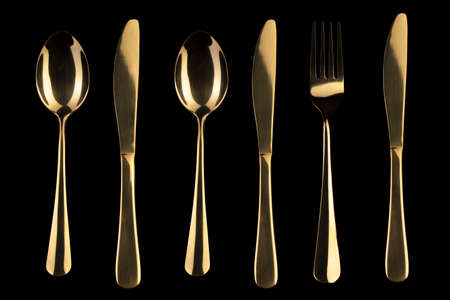 Gold knife and spoon and fork on a black background. Cutlery.の写真素材