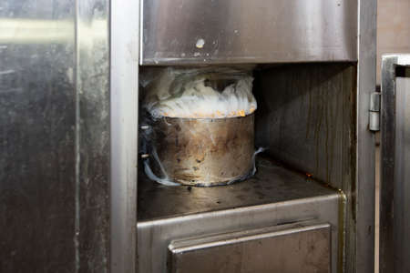 Metal pot with sawdust and smoke in an industrial oven for smoking fish.