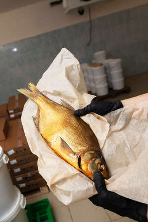 Smoked mackerel in hands in a warehouse.の写真素材