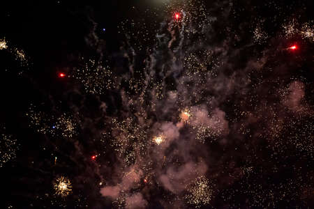 On a black background, ash spots and rays of fireworks with smoke. Festive dark background.