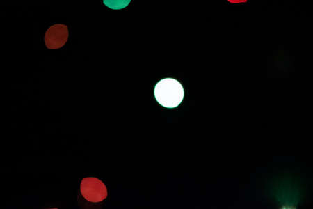Rare bright spots of multicolored bokeh on a black background.