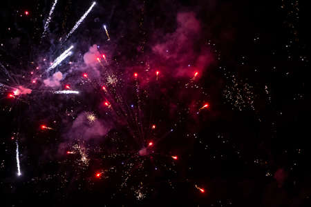 Red and purple rays of fireworks with smoke on black background. Festive night background.
