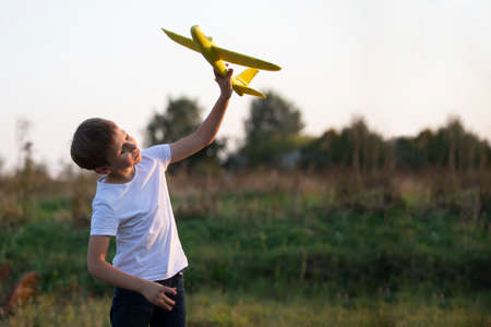 Little boy in the field plays with a yellow plane.の写真素材