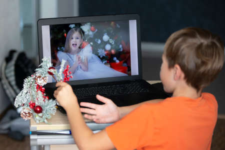 The child is sitting at a laptop and talking via video link with a friend. Staying at home,...