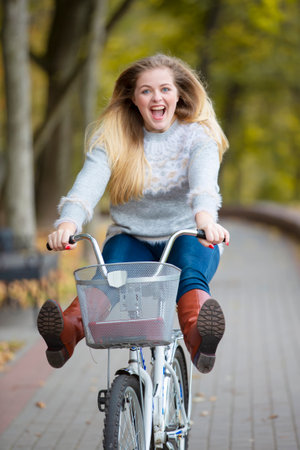 Young beautiful woman rides a bicycle in the autumn park.の写真素材