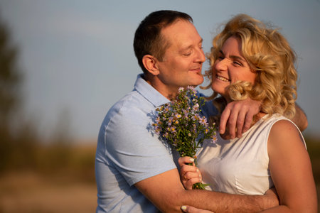 Beautiful middle-aged couple in love hugging on the background of nature.の写真素材