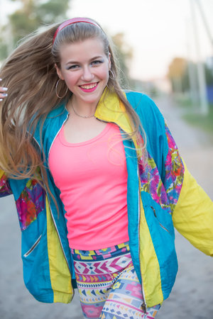 Beautiful blonde girl dressed in the style of the nineties dancing on the street.の写真素材