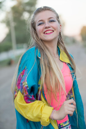 Beautiful blonde girl dressed in the style of the nineties dancing on the street.の写真素材