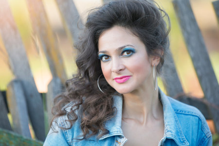 Beautiful young woman in a denim jacket with bright makeup in the style of the eighties against the...