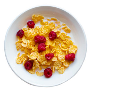 Cornflakes with raspberries on a white plate on a white background.の写真素材