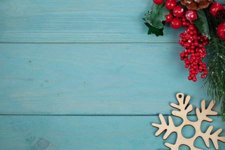 On a turquoise wood background, a decoration of a fir branch, cones and wood snowflakes. Christmas background.の写真素材
