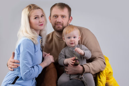 On a gray background family of three people mom dad and baby.