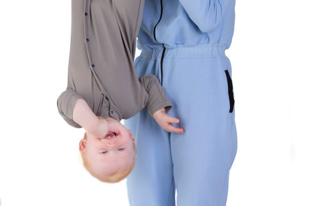 The happy baby is held by the legs, head down. Exercises for a one-year-old child.の写真素材