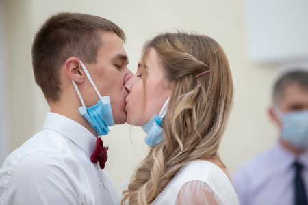 The bride and groom are kissing in medical masks. Wedding during the coronavirus panademia.の写真素材
