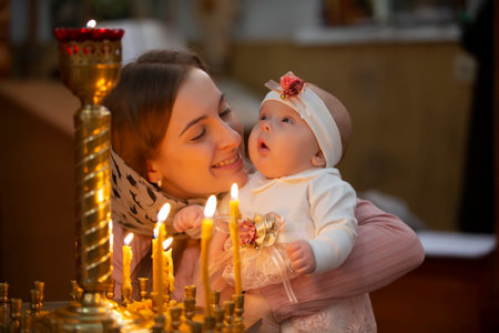 Mother and child in a church by candlelight. Woman with a baby in the temple.