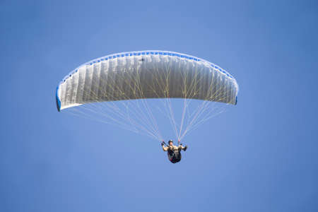 Belarus city Gomel October 7, 2018. Performances on paragliding.A paraglider flies in the sky under a multi-colored paraglider.Man under parachuteのeditorial素材