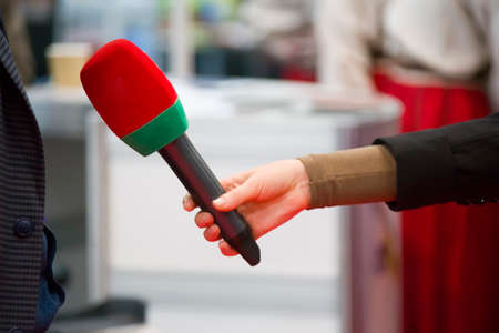 A hand is holding a microphone. Interviewの写真素材