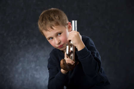 Boy with a gun. The child plays with the weapon. Six seven year old toddler with retro boobの写真素材