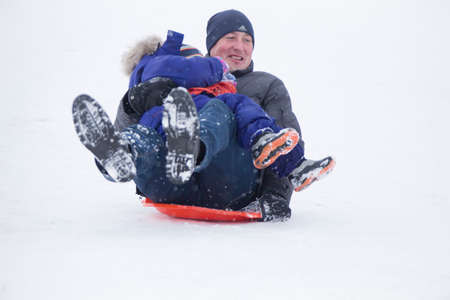 Belarus, the city of Gomel, December 31, 2018. The central quarter. People ride on a snow slide.Dad and son are riding down the snow toboggansのeditorial素材
