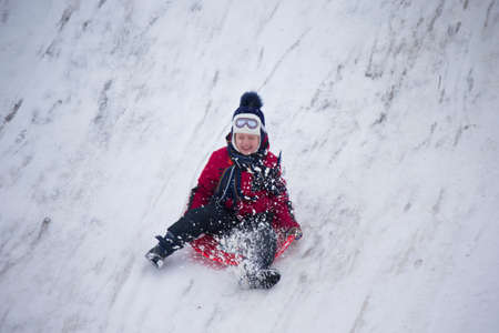 Belarus, the city of Gomel, December 31, 2018. The central quarter. People ride on a snow slide.The girl rides on sleds ice-boats from a hillのeditorial素材