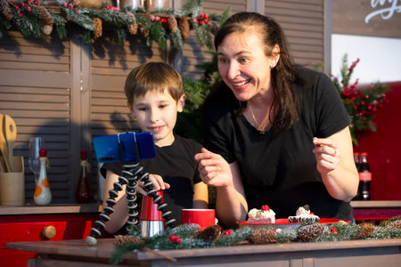 A little boy and mom are recording a stream or video on YouTube on a smartphone in the home kitchen.のeditorial素材