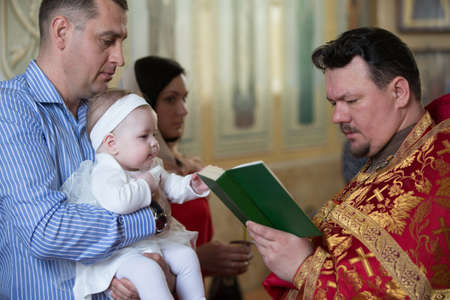 Belarus, Gomel, April 29, 2018. Church of Volotovo. Baptism of a newborn child. The Godfather keeps...