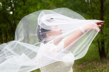 The fat bride covered herself with a wedding veil.の写真素材