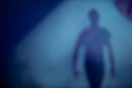 Blurred silhouette of a man in stage smoke. The departing ghost of a man. Dream mystical background...