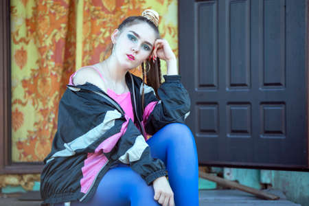 A beautiful girl in bright clothes sits on the porch of a village house. Woman in the style of the...