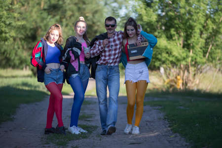 A man with a cassette tape recorder and beautiful girls dressed in the style of the nineties.の写真素材