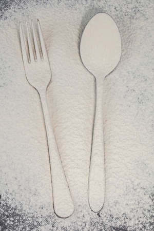 A fork and spoon on a cutting board are sprinkled with flour.Cutlery on the board.