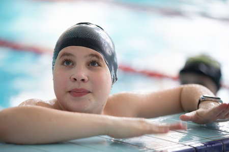 Boy in a swimming cap and swimming goggles in the pool. The child is engaged in the swimming...