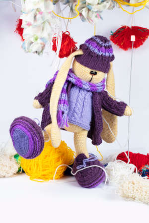 Funny knitted purple toy hare in tangles of threads.の写真素材