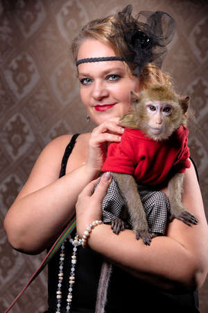 Retro female portrait in the style of 20s or 30s. A gorgeous lady is holding a little monkey.の写真素材