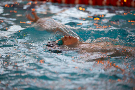 Boy in a swimming cap and swimming goggles in the pool. The child is engaged in the swimming section.の写真素材