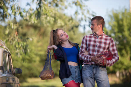A girl and a guy dressed in the style of the nineties are holding nets with food and talking.