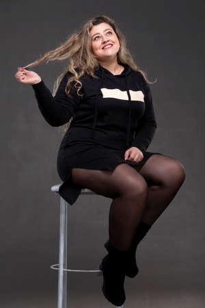 A beautiful fat woman with long curly hair sits on a chair.の写真素材