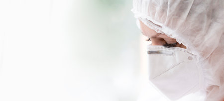 The face of a doctor in a protective medical mask and suit close-up on a white background.の写真素材