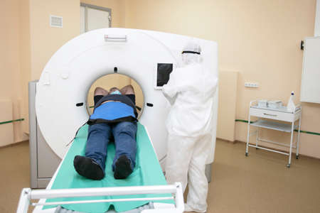 Doctors in protective medical suits are doing an MRI scan to a patient with coronavirus infection.