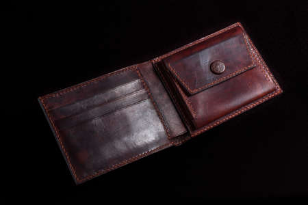 Leather open wallet in brown on a black background.