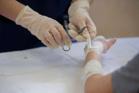 The doctor ties the patient's hand with a medical bandage.の写真素材