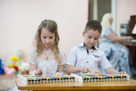 Belarus, the city of Gomil, 26.04.2019 Kindergarten in the city. A boy and a girl of preschool age play a xylophone at a matinee in kindergarten.のeditorial素材