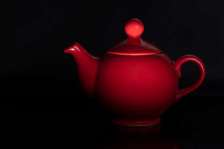 Teapot of red color of the classical form on a black background.の写真素材