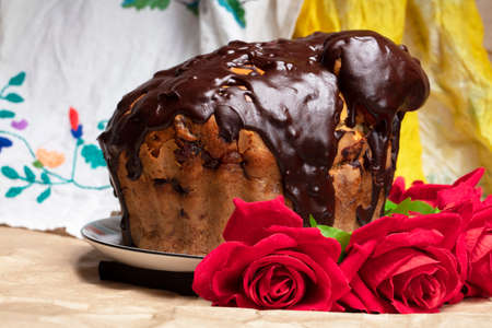 Beautiful Easter background. Chocolate cake with red roses on the background of an embroidered shirt.の写真素材
