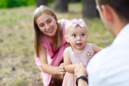 Husband, wife and their little daughter for a walk in the park. Happy dad and mom with one year old...