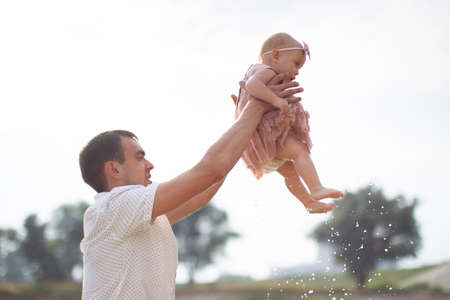 Happy dad throws up with his little daughter for a walk. Paternity.の写真素材