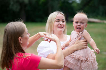 A little girl is crying in her mother's arms.