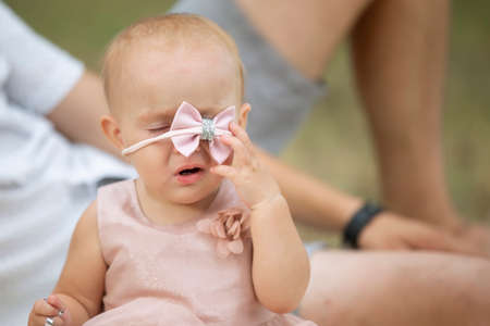 A funny little girl removes a beautiful jewelry from her head. The child is one year old.の写真素材