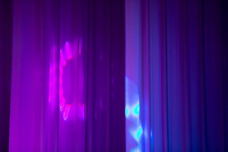 Multicolored rays of light from a stage spotlight on a blue background.